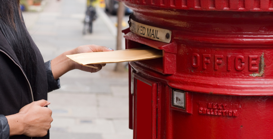 Image of a women placing a letter into a red letter box.